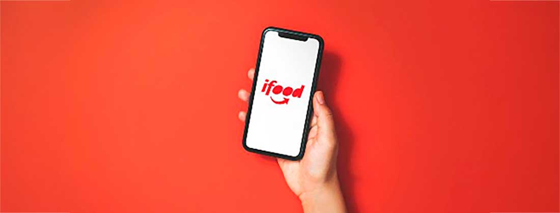 Mão segurando o celular com a tela do ifood aberta.